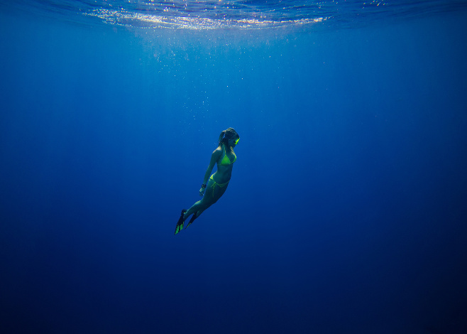 girl swimming underwater in deep blue tropical sea
