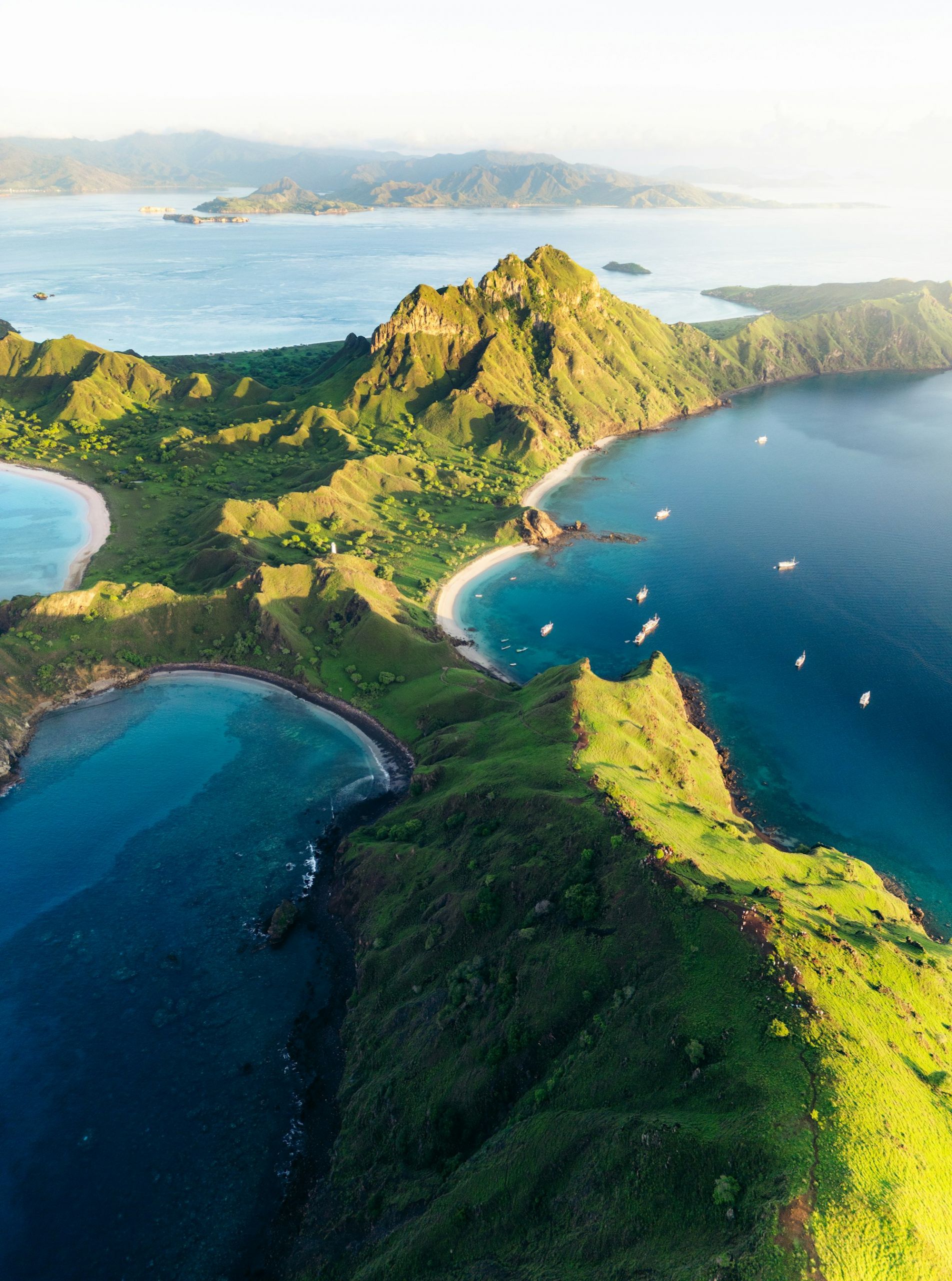 Aerial view of an island in Komodo with several boats on the water