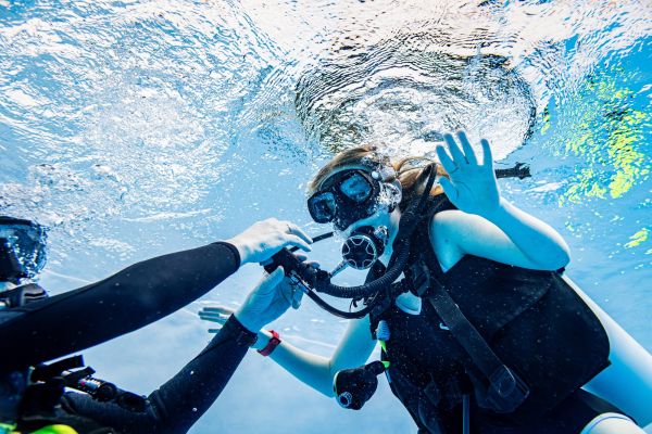 Scuba instructor guiding a student underwater during a pool training lesson