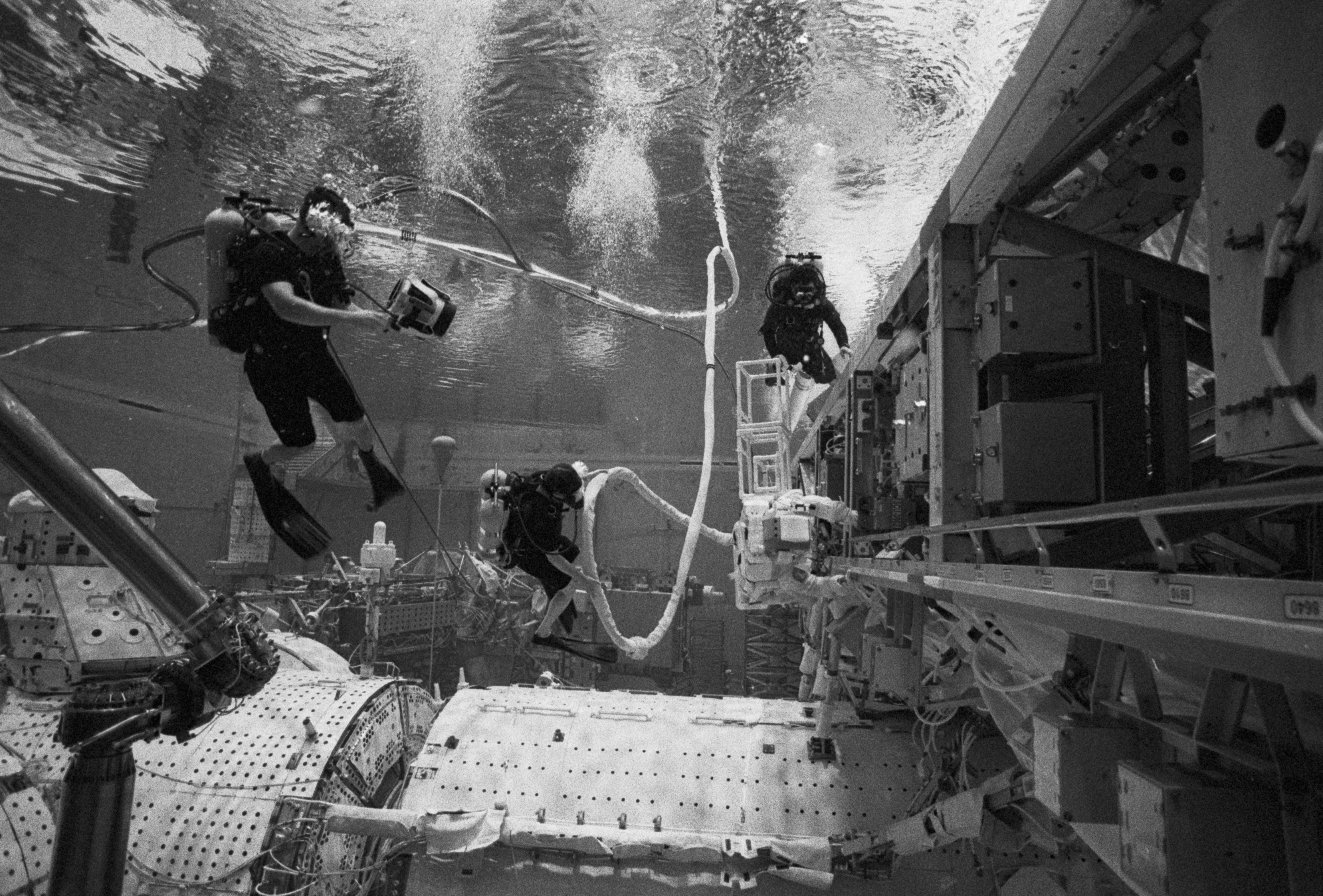 Making their way down the main truss segment of the ISS, a NASA crew member is assisted by divers to ensure a smooth transition in simulated flight-like conditions. Photo by Moe Lauchert.
