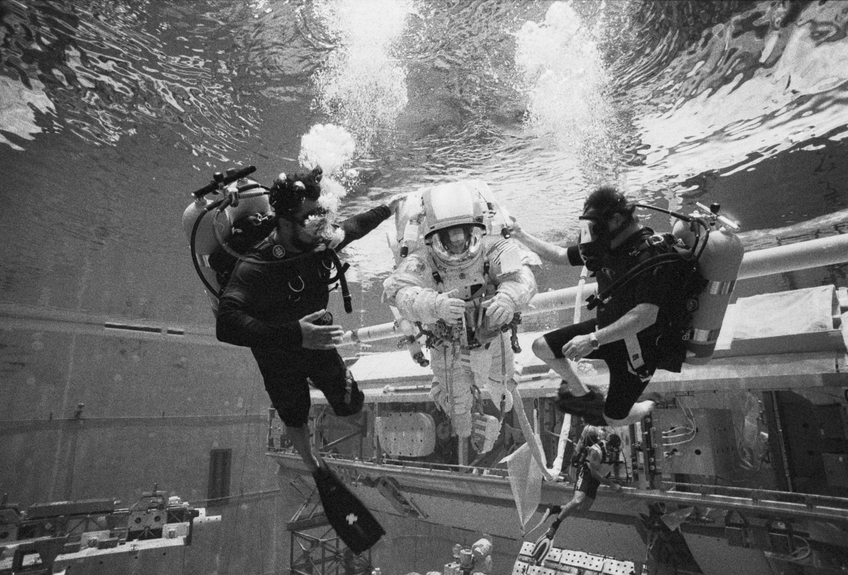 Divers swim the NASA crew member over the truss to the downline for descent. Photo by Moe Lauchert.